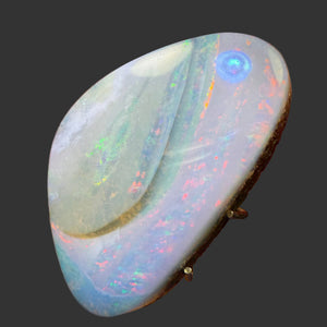 Close-up of a colorful opal stone held between fingers